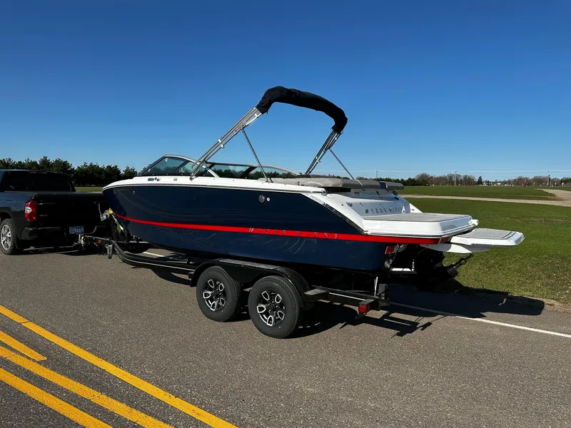 Slide: The Image of 2023 Four Winns H2 boat on trailer, parked on a road under clear blue sky. - 3