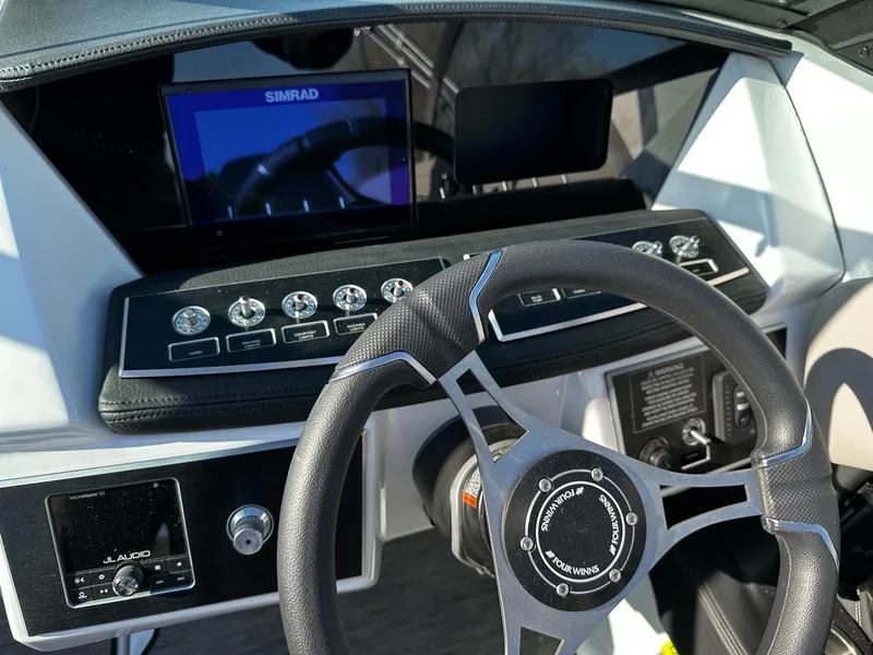 Slide: The Image of 2023 Four Winns H2 boat dashboard with steering wheel, Simrad display, and control panel. - 7
