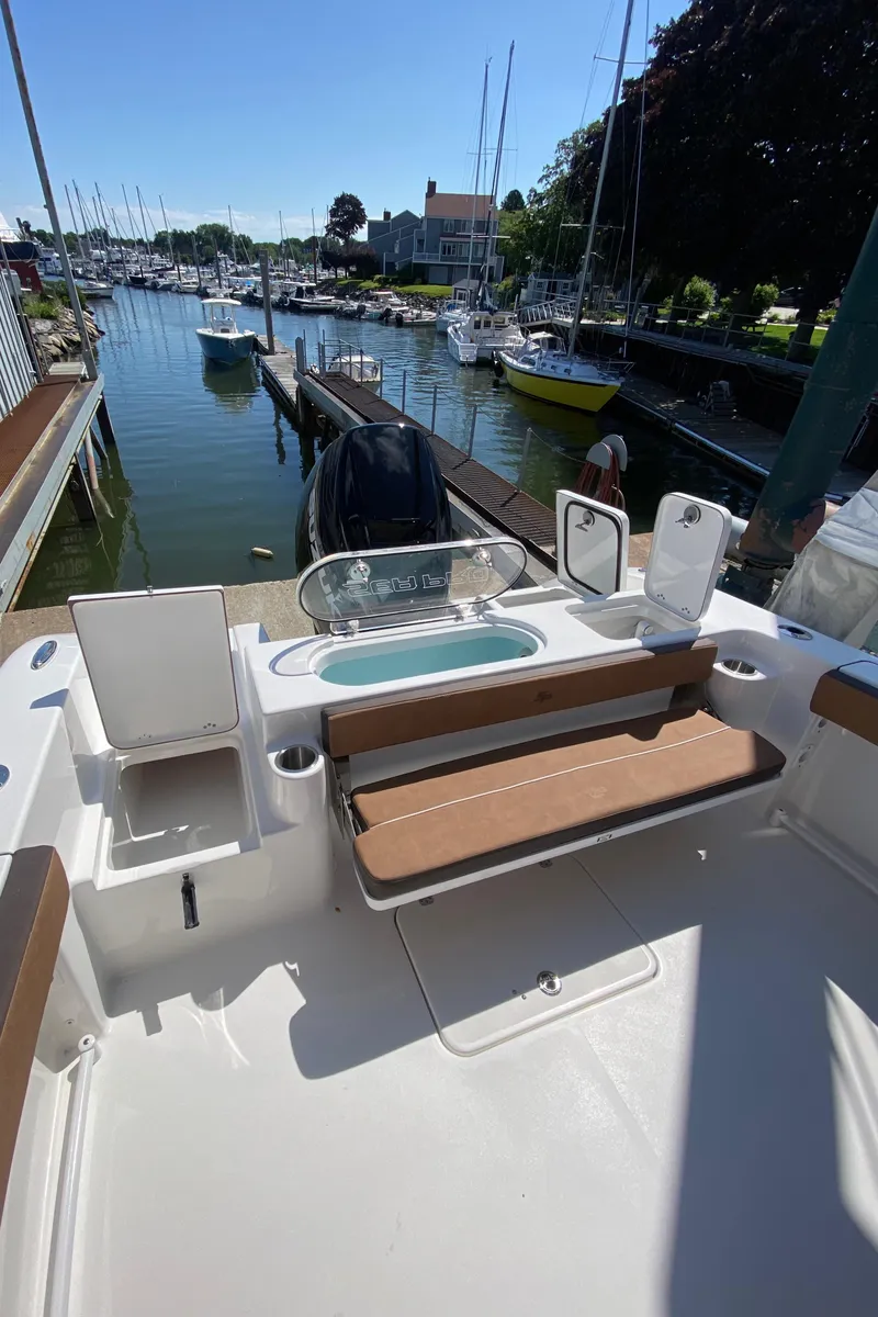 Slide: The Image of 2024 Sea Pro 240 Dual boat docked at a marina with seating and storage compartments. - 8