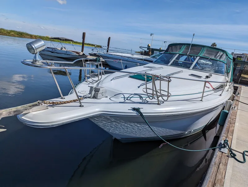 The Image of 1992 Sea Ray 330 Express Cruiser on calm water with green canopy. - 0