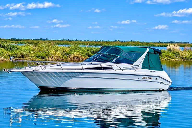 The Image of 1992 Sea Ray 330 Express Cruiser on calm water under a clear blue sky. - 0