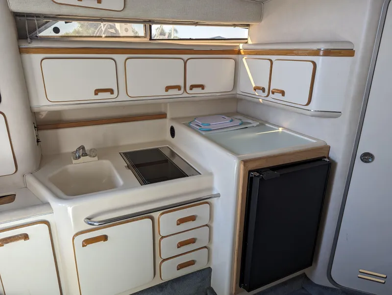 Slide: The Image of 1992 Sea Ray 330 Express Cruiser kitchen with sink, stove, and compact fridge. - 9