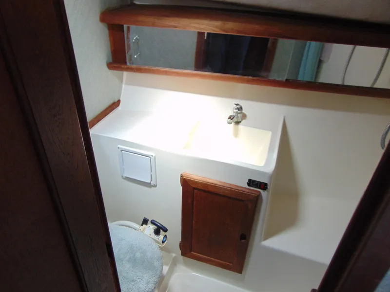 Slide: The Image of 1991 Bayliner 3288 Motoryacht bathroom with sink, mirror, and wooden cabinet. - 12