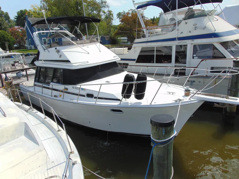 Slide: The Image of 1991 Bayliner 3288 Motoryacht docked at marina, surrounded by other boats. - 3