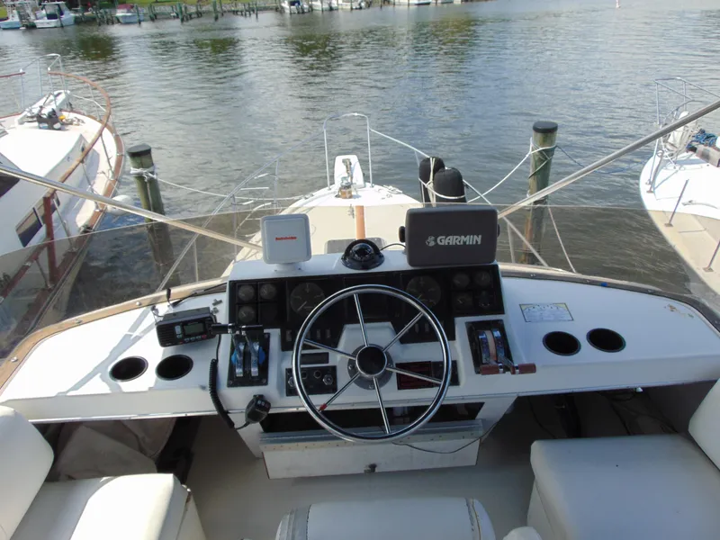Slide: The Image of 1991 Bayliner 3288 Motoryacht helm with steering wheel and navigation equipment, docked by the water. - 6