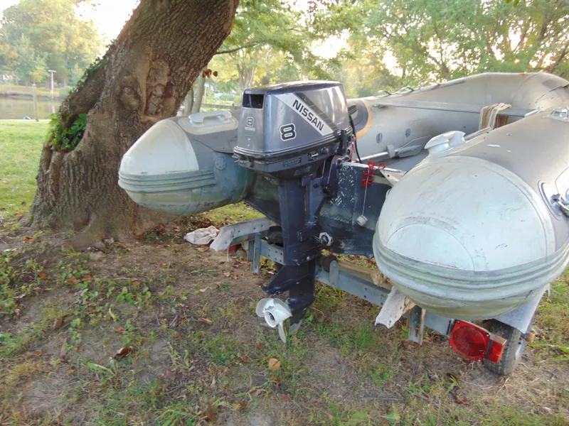 Slide: The Image of 2021 North Atlantic Inflatables DINK with Nissan motor, parked on grass near a tree. - 2