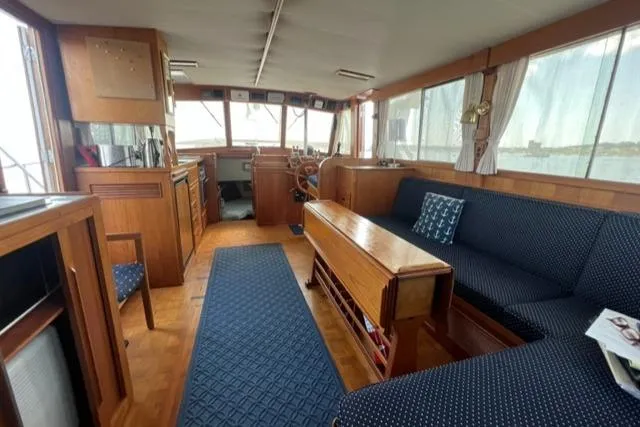 Slide: The Image of Interior of 1987 Grand Banks 42 Classic Trawler, featuring wood paneling and blue upholstery. - 2