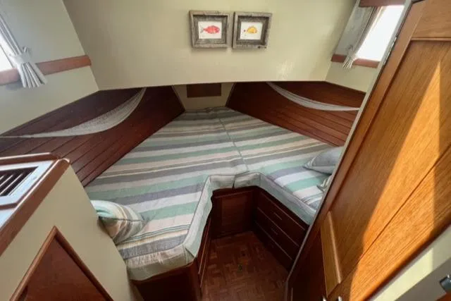 Slide: The Image of 1987 Grand Banks 42 Classic Trawler cabin with striped bedding and wooden interior. - 24
