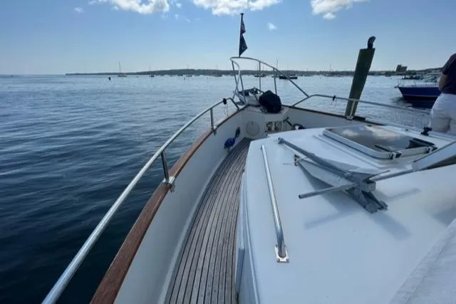 Slide: The Image of 1987 Grand Banks 42 Classic Trawler on calm waters, showcasing deck and railing. - 31