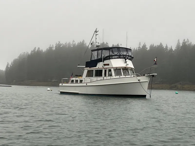 Slide: The Image of 1987 Grand Banks 42 Classic Trawler on misty water with forested background. - 50
