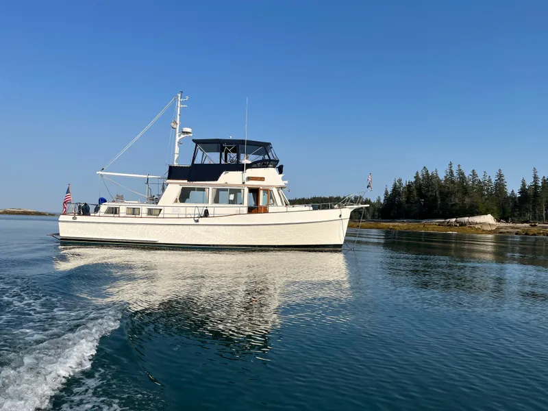 Slide: The Image of 1987 Grand Banks 42 Classic Trawler cruising on calm waters, clear blue sky backdrop. - 51