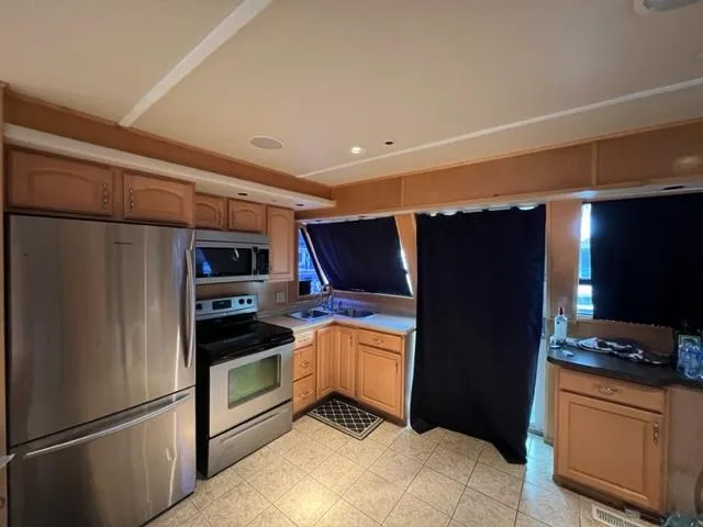 Slide: The Image of 1988 Stardust Cruisers houseboat kitchen with stainless steel appliances and wooden cabinets. - 4
