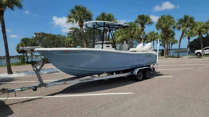 Slide: The Image of 2017 Sea Chaser 24 HFC boat on a trailer in a parking lot near palm trees. - 11