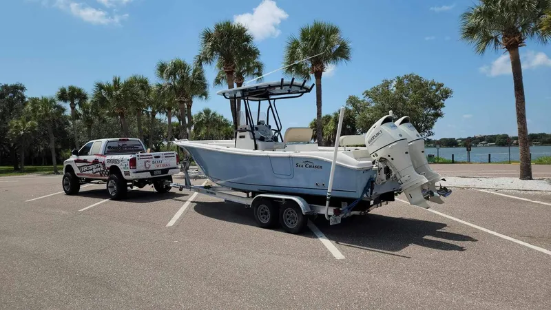 Slide: The Image of 2017 Sea Chaser 24 HFC boat on trailer, parked near waterfront with palm trees. - 17