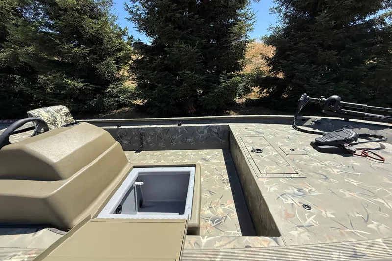 Slide: The Image of 2024 Tracker Grizzly 1754 SC boat interior with camouflage design, featuring storage compartments and steering console. - 7