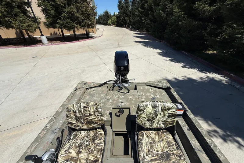 Slide: The Image of 2024 Tracker Grizzly 1754 SC boat with camouflage seats on a sunny day. - 8