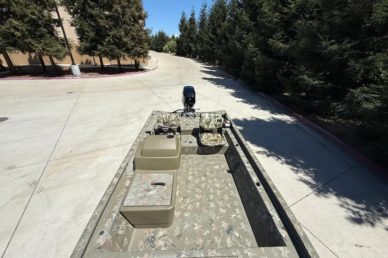 Slide: The Image of 2024 Tracker Grizzly 1754 SC boat on a paved road, surrounded by trees. - 11