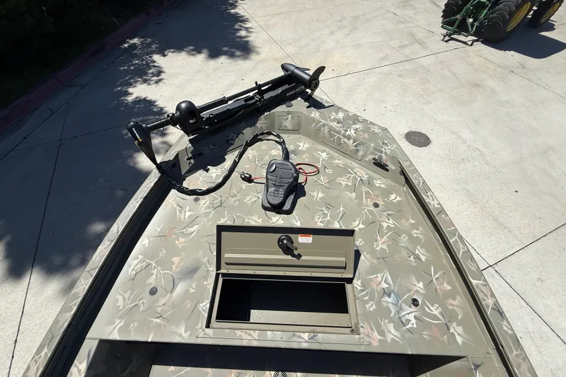 Slide: The Image of 2024 Tracker Grizzly 1754 SC boat with camouflage design and trolling motor on concrete surface. - 5