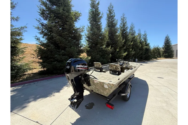 Slide: The Image of 2024 Tracker Grizzly 1754 SC boat with Mercury engine, parked outdoors near trees. - 3
