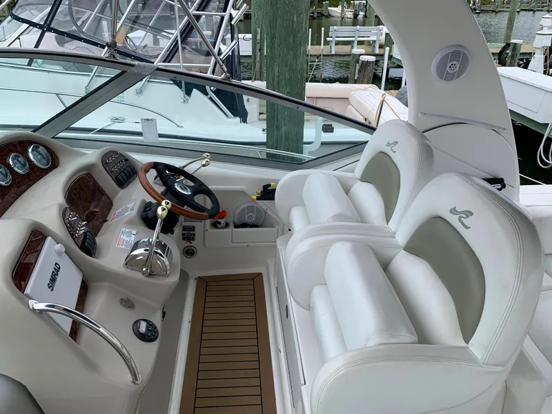 Slide: The Image of 2006 Sea Ray 340 Sundancer helm with white leather seats and wooden steering wheel. - 21