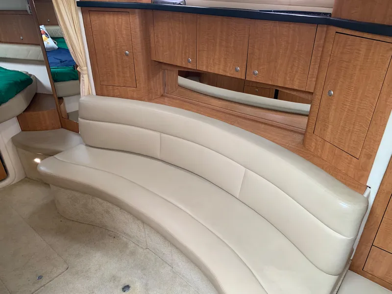 Slide: The Image of 2006 Sea Ray 340 Sundancer interior with curved beige leather seating and wooden cabinetry. - 29
