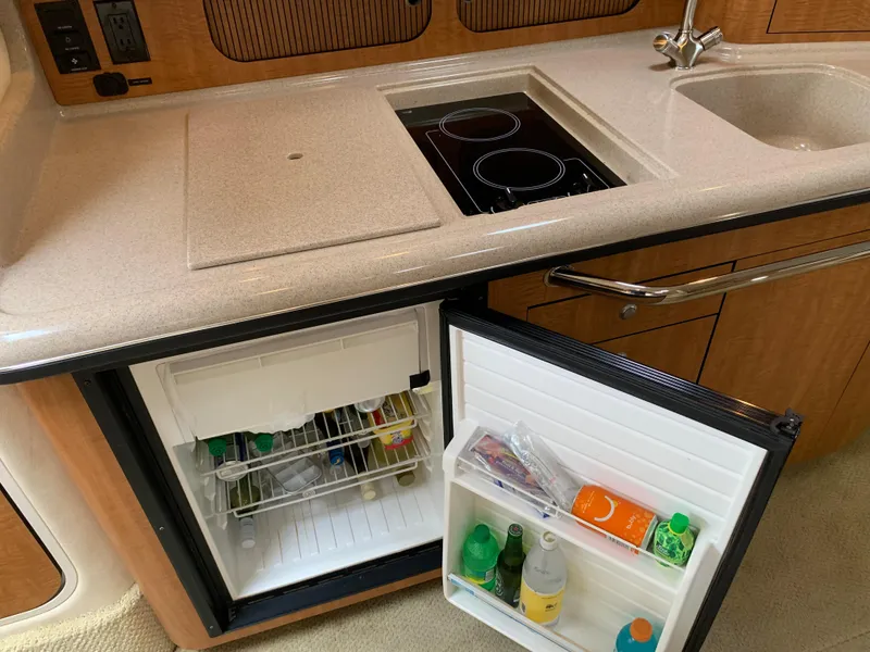 Slide: The Image of 2006 Sea Ray 340 Sundancer galley with open fridge, sink, and stove. - 31