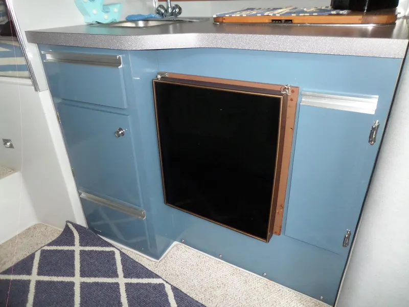 Slide: The Image of 1986 Wellcraft Monte Carlo 2800 boat interior kitchen with blue cabinets and mini fridge. - 40