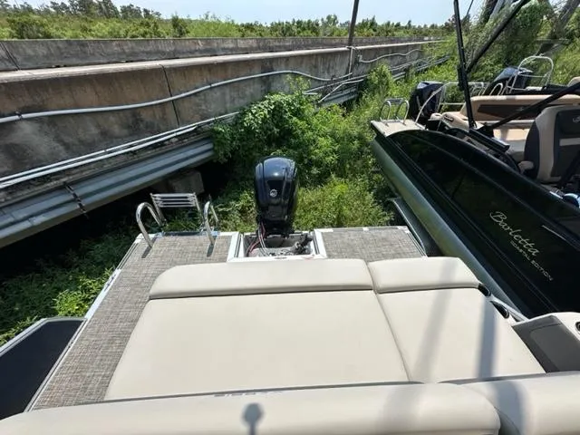 Slide: The Image of 2023 Harris 210 Cruiser boat with outboard motor near a bridge and greenery. - 15