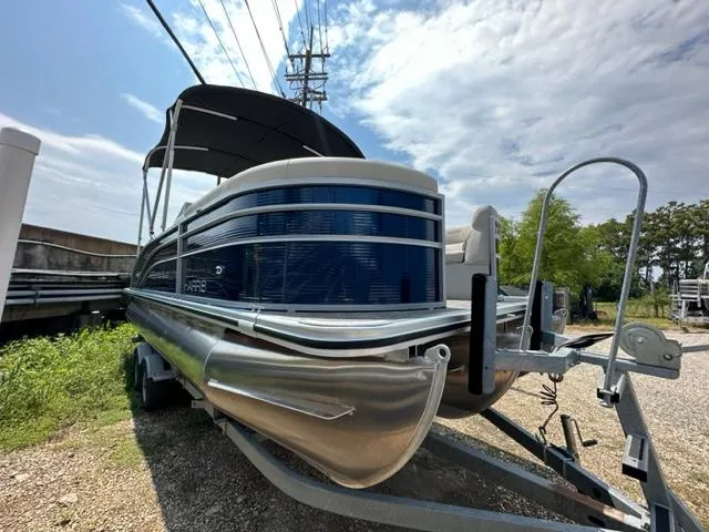 Slide: The Image of 2023 Harris 210 Cruiser pontoon boat on a trailer under a partly cloudy sky. - 3