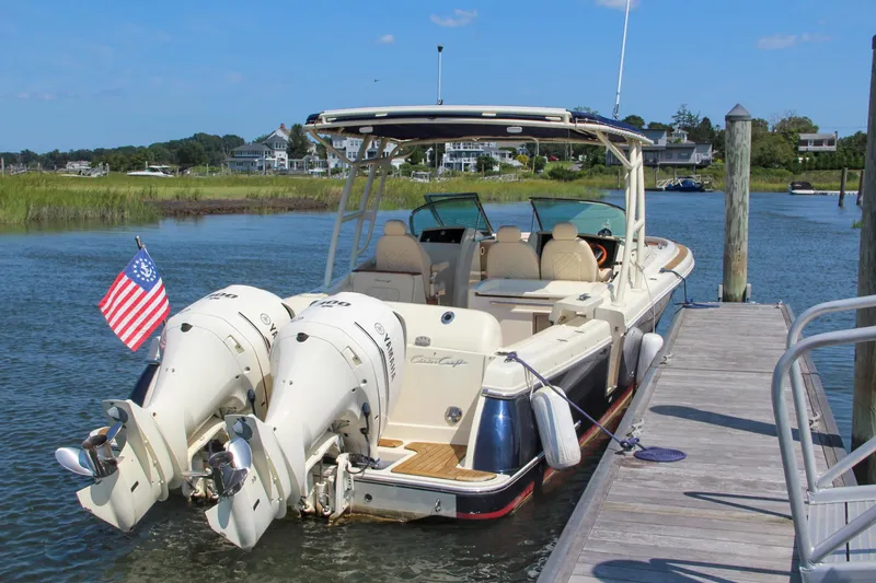 Slide: The Image of 2017 Chris-Craft Calypso 30 docked, featuring dual outboard engines and American flag. - 0