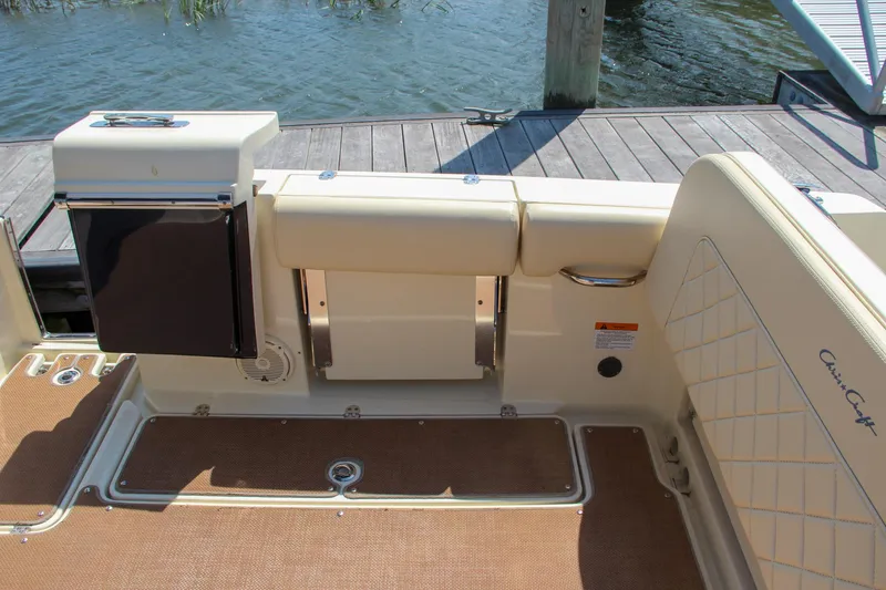 Slide: The Image of 2017 Chris-Craft Calypso 30 boat interior with seating and storage, docked by the water. - 13