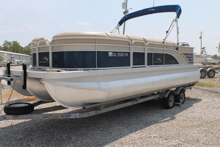 Slide: The Image of 2015 Bennington 2275 GCW pontoon boat on trailer, featuring blue and beige design. - 0