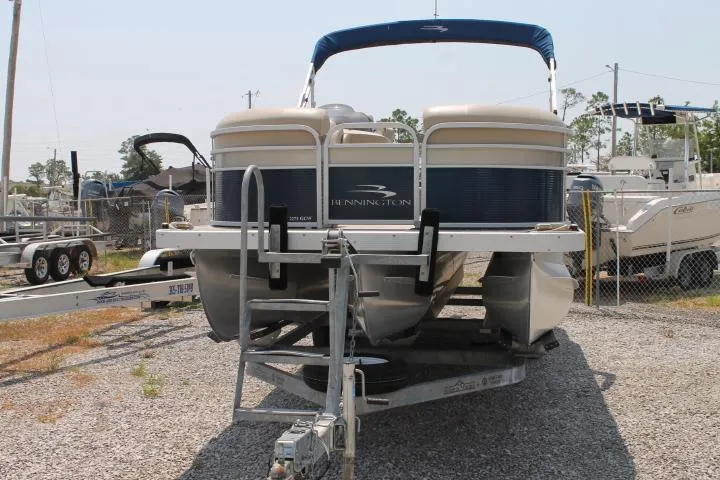 Slide: The Image of 2015 Bennington 2275 GCW pontoon boat on trailer, parked in a gravel lot. - 2