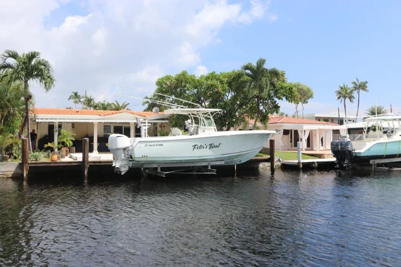 Slide: The Image of 2013 Sailfish 320 CC boat docked by waterfront homes. - 1