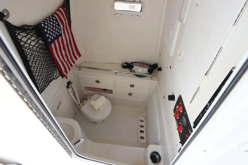 Slide: The Image of 2013 Sailfish 320 CC boat interior with toilet, storage, and American flag. - 8