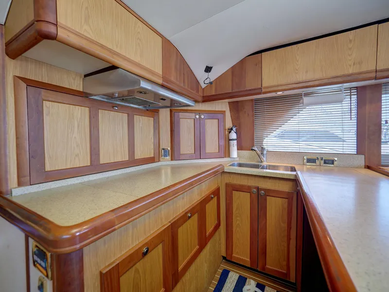 Slide: The Image of 2005 Luhrs 41 Convertible yacht kitchen with wooden cabinets and countertops. - 16
