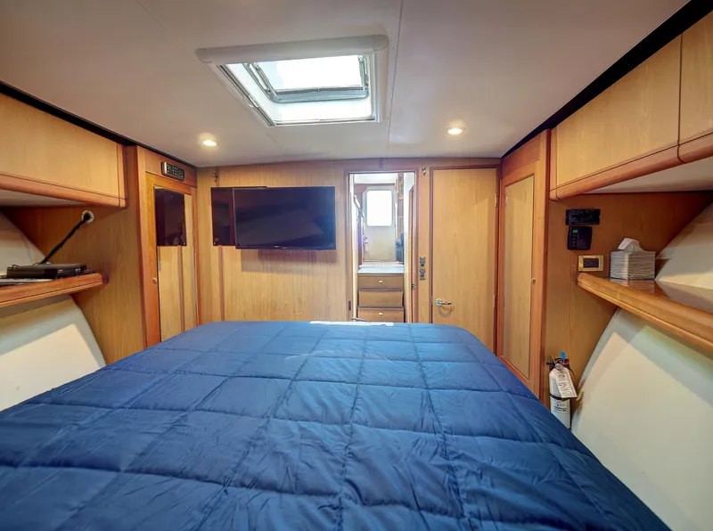 Slide: The Image of 2005 Luhrs 41 Convertible cabin with skylight, TV, and blue bedding. - 19