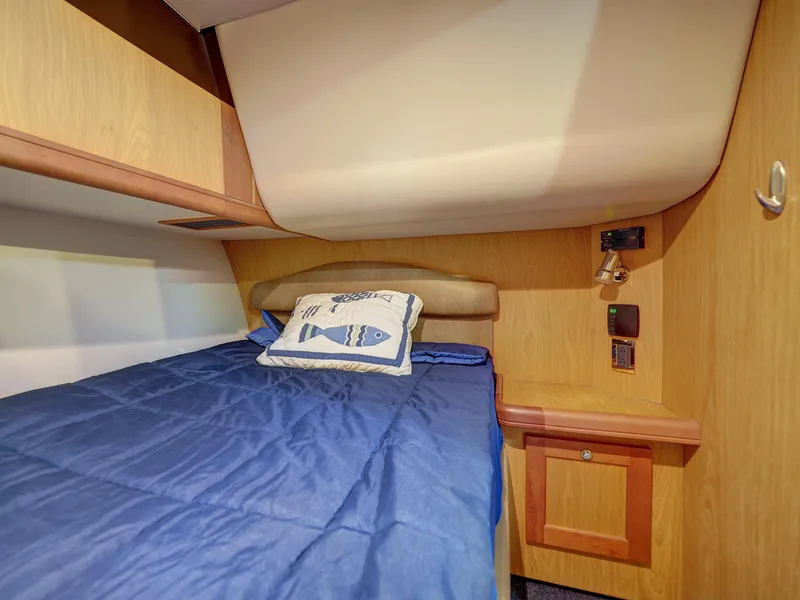 Slide: The Image of 2005 Luhrs 41 Convertible cabin with blue bedding and fish-themed pillow. - 24