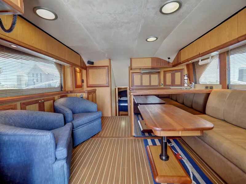 Slide: The Image of 2005 Luhrs 41 Convertible yacht interior with wooden finishes, blue chairs, and a dining area. - 7