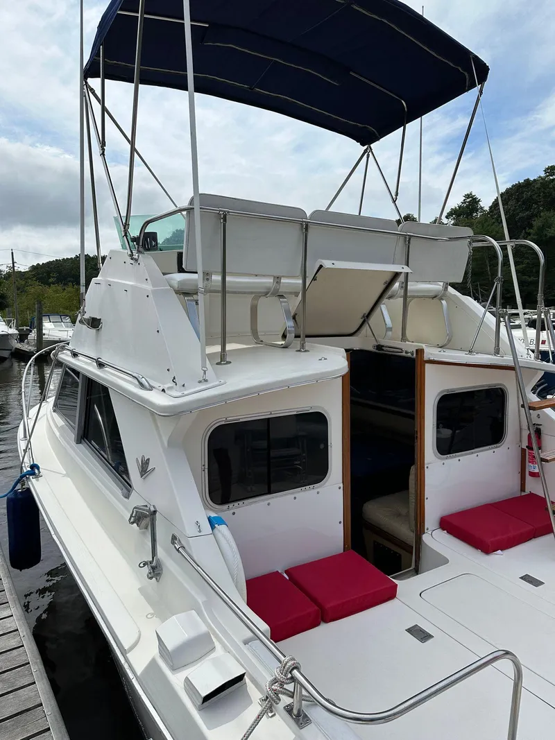 Slide: The Image of 1983 Bertram 28 boat with flybridge and red cushions docked at marina. - 11
