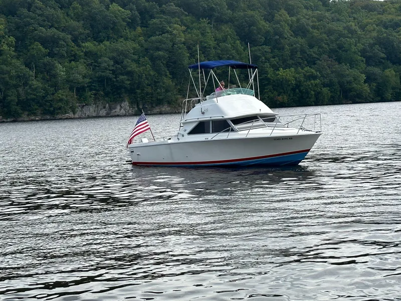 Slide: The Image of 1983 Bertram 28 boat on a lake with forested shoreline. - 3