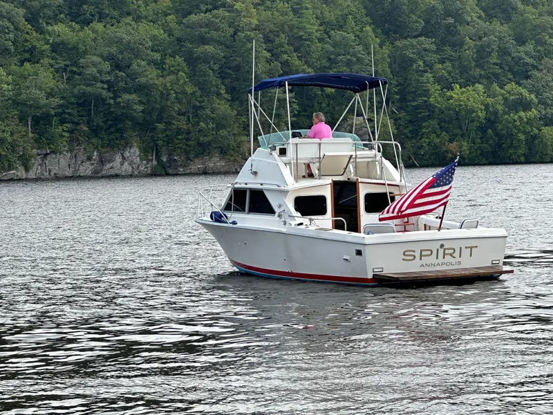 Slide: The Image of 1983 Bertram 28 boat named Spirit on a lake with forested background. - 4