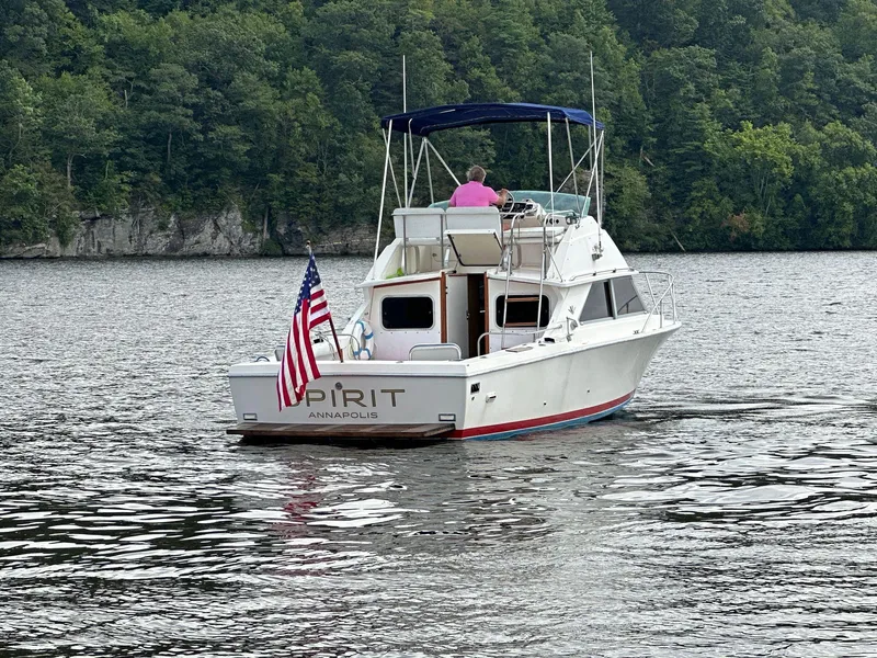 Slide: The Image of 1983 Bertram 28 boat named Spirit cruising on a lake with forested shoreline. - 5