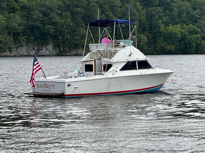 Slide: The Image of 1983 Bertram 28 boat named Spirit on a lake with forested background. - 6
