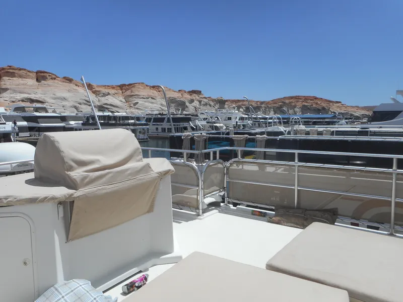 Slide: The Image of Houseboats docked at a marina with rocky cliffs in the background under a clear blue sky. - 10