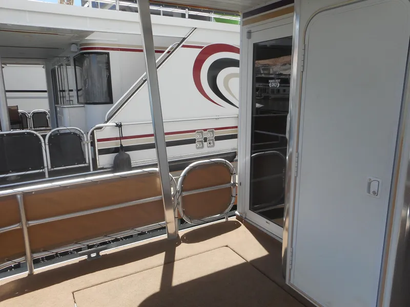 Slide: The Image of Houseboat deck with railing, featuring a 2004 Sharpe Mysterious Waves model in the background. - 13