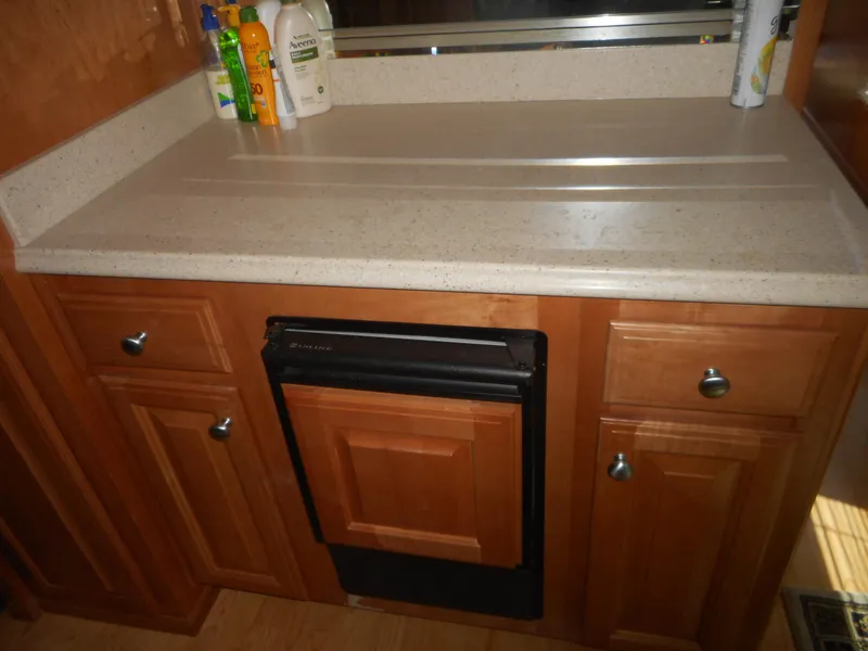 Slide: The Image of Wooden kitchen cabinet with countertop, featuring cleaning products. Sharpe Mysterious Waves, 2004 model. - 28