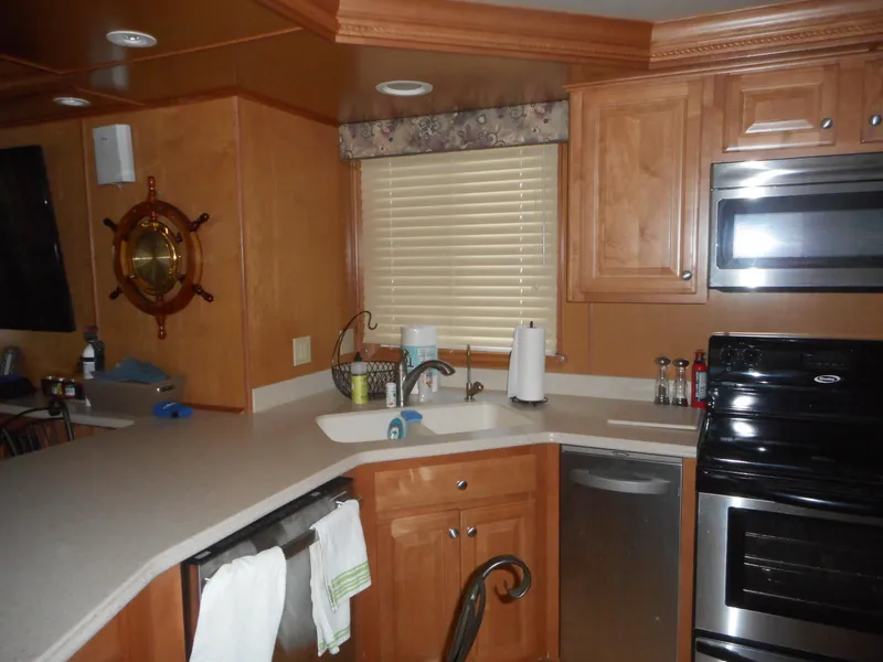 Slide: The Image of Modern kitchen interior in a 2004 Sharpe Mysterious Waves houseboat, featuring wooden cabinets and stainless appliances. - 30