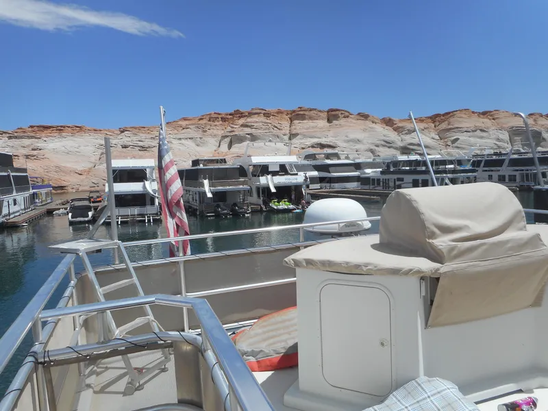 Slide: The Image of Houseboats docked at a marina with rocky cliffs in the background, under a clear blue sky. - 9