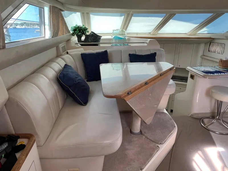 Slide: The Image of 1997 Sea Ray 420 Aft Cabin interior with white leather seating and dining table. - 22